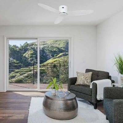 Ventilateur de plafond silencieux installé dans un salon lumineux avec canapé, table basse et vue extérieure. comment choisir un ventilateur de plafond silencieux