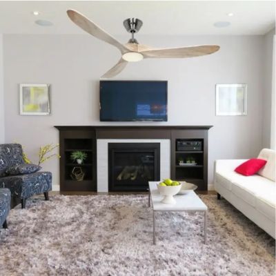 Ventilateur plafond silencieux bois au-dessus d’un salon moderne avec canapé blanc, cheminée et table basse.