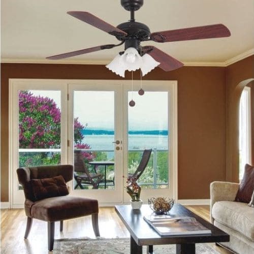 Ventilateur plafond avec lumière faro installé dans un salon lumineux, avec vue sur balcon et extérieure verdoyante.